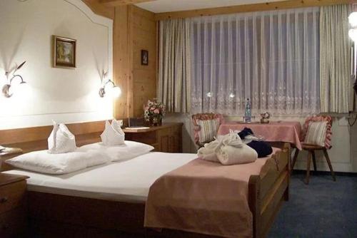 a hotel room with two beds and a table at Hotel Edelweiẞ garni - b&b in Berwang
