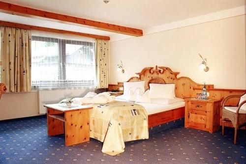 a bedroom with a large bed and a desk at Hotel Edelweiẞ garni - b&b in Berwang