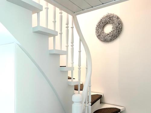 a white staircase with a donut hanging on the wall at Romantikhaus am Hafen in Greetsiel in Greetsiel