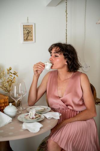a woman sitting at a table drinking from a cup at Casa Viola Bed and Breakfast Dimora di campagna in Calice Ligure