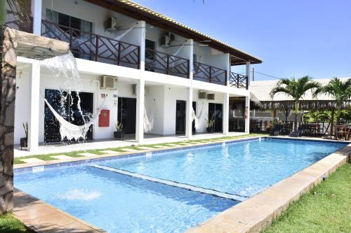 a swimming pool in front of a building at Milano Hotel Pousada Canoa Quebrada in Canoa Quebrada