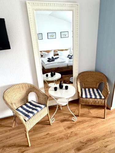 two chairs and a table in a room with a mirror at Meerblick Apartment in Göhren