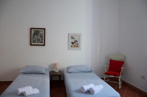 two beds in a room with a red chair at On the Tuscan coast in Piombino