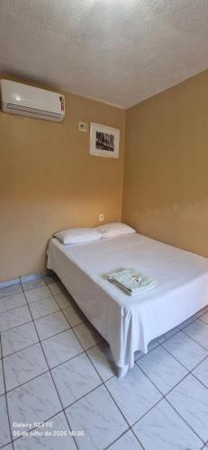 a bed in a room with a sign on the wall at Hotel Avenida in Acailandia
