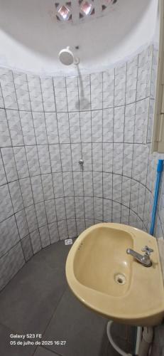 a bathroom with a sink and a white tiled wall at Hotel Avenida in Acailandia