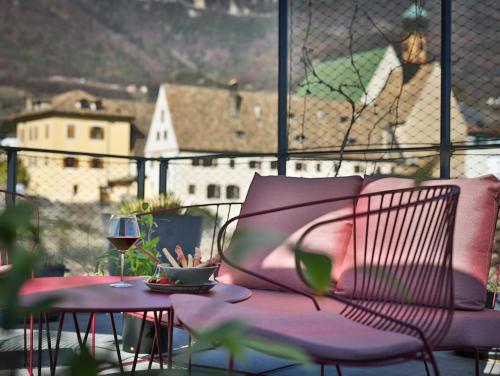 a pink chair and a table with a glass of wine at Goldengel Design - Suiten im historischen Ortskern von Kaltern in Caldaro