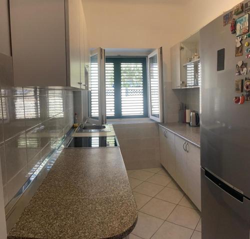 a kitchen with white cabinets and a large window at Suzy apartment, Dugi Rat in Dugi Rat