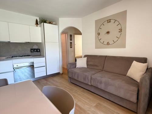 a living room with a couch and a clock on the wall at Moderno appartamento con giardino in Carisolo