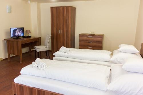 a room with three beds and a desk with a computer at M1 Szekér Csárda Hotel és Étterem in Obarok