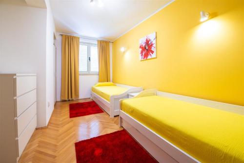 a yellow room with two beds and a window at Beach Villa Ratac in Slano