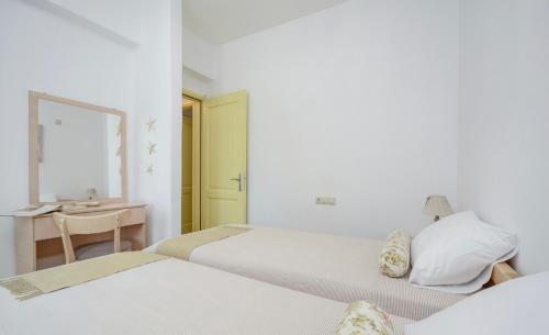 two beds in a room with a desk and a sink at Kapris House in Agios Prokopios