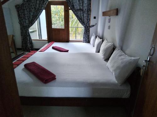 a bedroom with a large white bed with two pillows at Sigiri Holiday Bungalow in Sigiriya