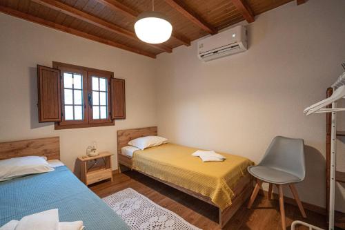 a bedroom with two beds and a chair in it at Casa da Praça in Freixo de Numão