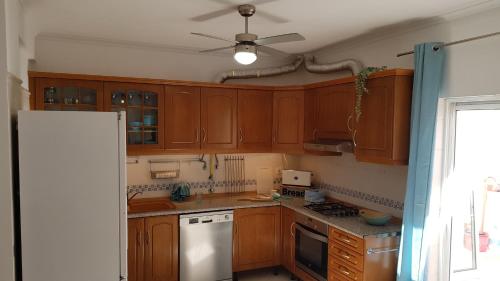 cocina con armarios de madera y ventilador de techo en Estrelinha da Fuzeta, en Fuseta