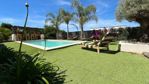 une cour avec une piscine et une pelouse avec une chaise dans l'établissement Villa Casa di Simone Pietrosella Corse du Sud, à Pietrosella