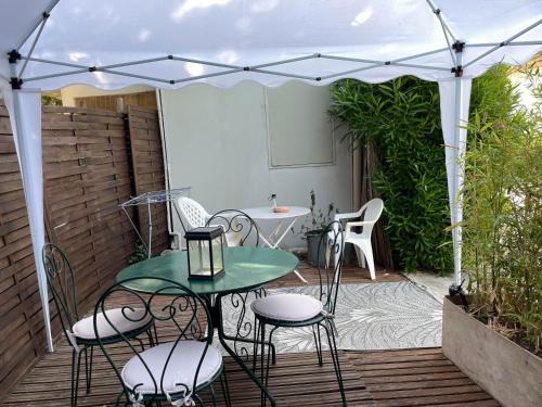 a patio with a table and chairs under an umbrella at Mas Grimaud - Gîte- Studio et chambres d'hôtes familiales in Eygalières