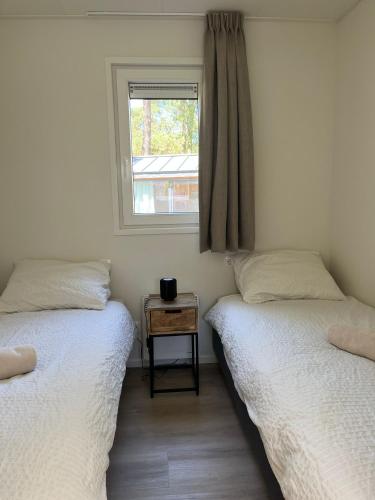 two twin beds in a room with a window at Sallands natuurhuisje Hellendoorn hottub Metz in Haarle