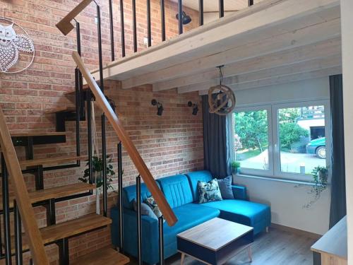 a living room with a blue couch and a brick wall at Domek Sasino in Sasino