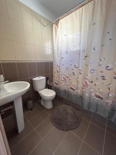 a bathroom with a toilet and a shower curtain with fish on it at Dene Hollow kapparis in Paralimni