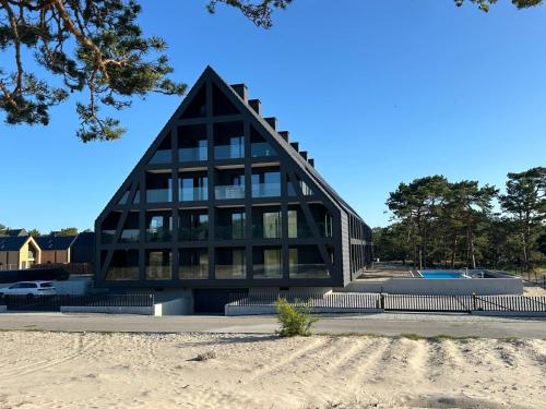 a building with a triangular roof on a beach at Czarna Perła Hel in Hel