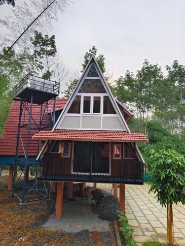 a house with a gambrel roof on top of it at River Valley Huts, Wayanad in Panamaram