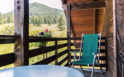 two chairs and a table on the porch of a cabin at Hotel Spa L'Equipe in Molines-en-Queyras