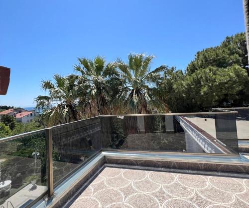 a balcony with a glass railing and palm trees at Cloud Nine by Alara - Luxury Private Pool and Garden Villa in Beylikduzu