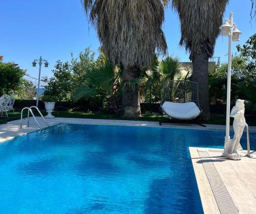 a blue swimming pool with a white chair and palm trees at Cloud Nine by Alara - Luxury Private Pool and Garden Villa in Beylikduzu