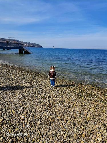 a girl standing on a rocky beach near the ocean at Istrabella Apartment in Koper