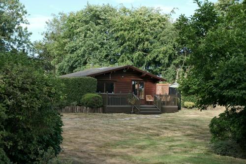 a small wooden cabin in a yard with trees at Countryside Log Cabin in Luton