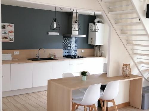 a kitchen with white cabinets and a table with chairs at Sérénité à la mer in Concarneau