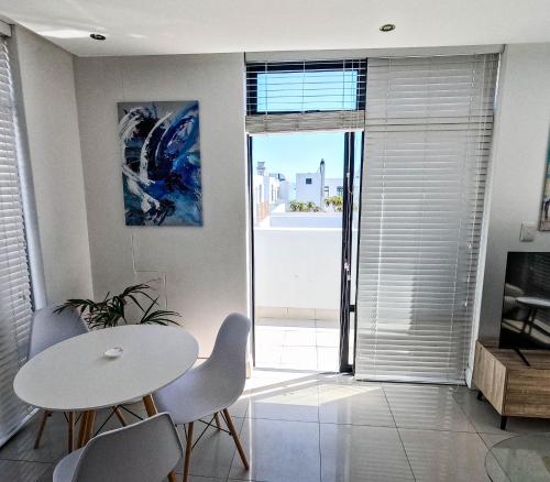 a dining room with a white table and chairs at Beachfront Penthouse with patio and free parking in Cape Town