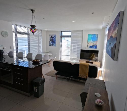 a living room with a couch and a table at Beachfront Penthouse with patio and free parking in Cape Town