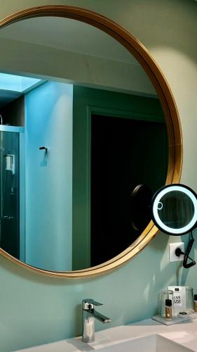 a mirror above a sink in a bathroom at Hôtel Villa la Renaissance in Bayonne