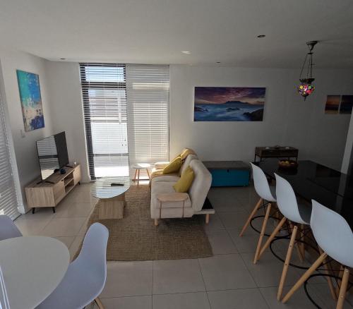 a living room with a couch and a table at Beachfront Penthouse with patio and free parking in Cape Town
