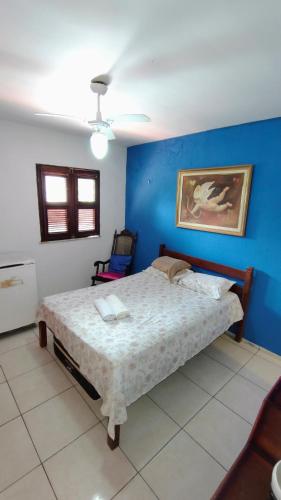 a bedroom with a bed with a blue wall at Suites Solar dos Arcanjos Guaramiranga in Guaramiranga