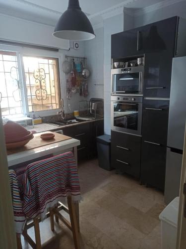a kitchen with black cabinets and a table and a stove at Meyssa's Paradise in Tangier