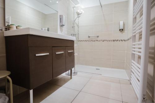 a bathroom with a sink and a shower and a tub at Logis Hotel des Granges in Arles