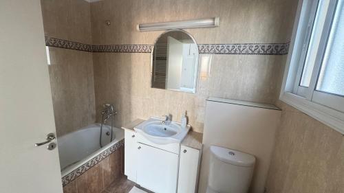 a bathroom with a sink and a toilet and a mirror at Olympus Holiday villa in Pissouri