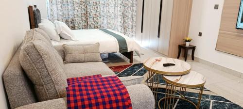 een woonkamer met een bank en een bed bij Cozy Ruaka Retreat in Ruaka