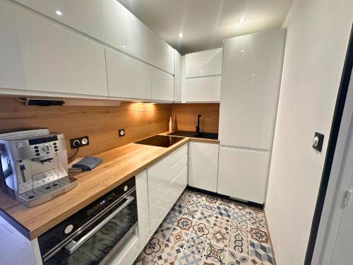 une cuisine avec des armoires blanches et un micro-ondes dans l'établissement Asteria by Pom, clim, pkg, wifi, au Cap d'Agde