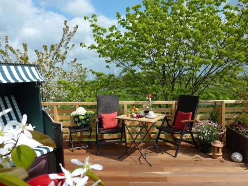 a patio with three chairs and a table on a deck at Ferienwohnung Wunschgarten in Wesselburen