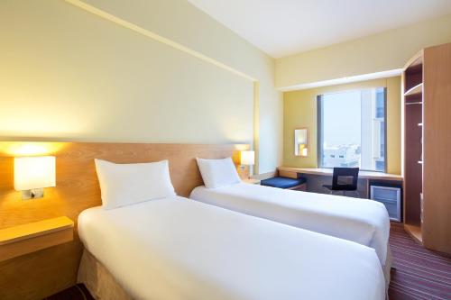 a hotel room with two beds and a window at ibis Dubai Al Rigga in Dubai