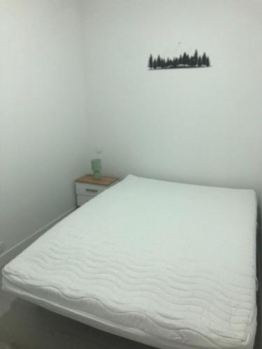 a white bed in a room with a picture on the wall at appt 8 pers tout confort 4 in Laveissière