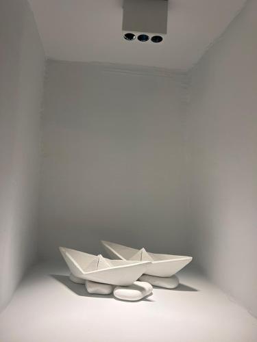 two white paper boats sitting in a white room at Entice Residence in Kóstos