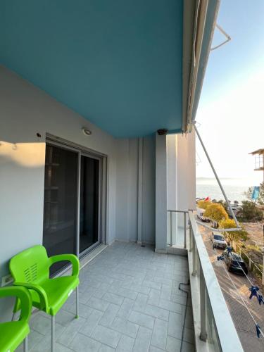 a balcony with a green chair on a building at Stylish Apartment 50m from Radhimë Beach in Vlorë