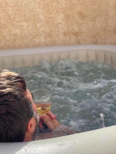 a man in a bath tub with a glass of wine at Sud Bastia 50 m2 privé avec jacuzzi et piscine in Monte