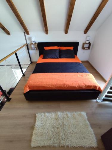 a bedroom with a bed with an orange blanket and a rug at Cottage in nature of Cetinje in Cetinje