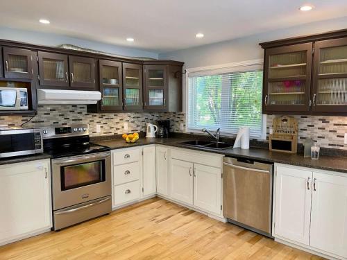 Una cocina con gabinetes blancos y electrodomésticos de acero inoxidable. en Spacious 3-Bedroom Main House in Bobcaygeon #12, en Kawartha Lakes