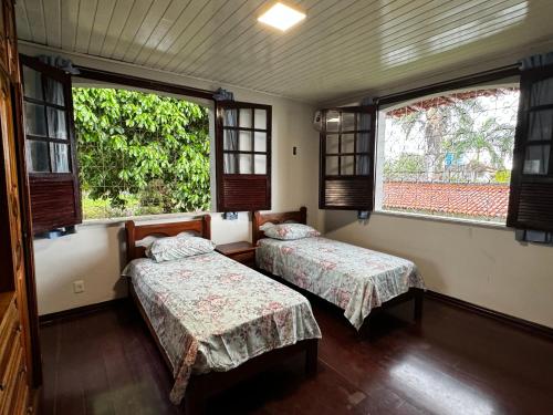 Dos camas en una habitación con dos ventanas. en Casarão do Lago, en Salinópolis